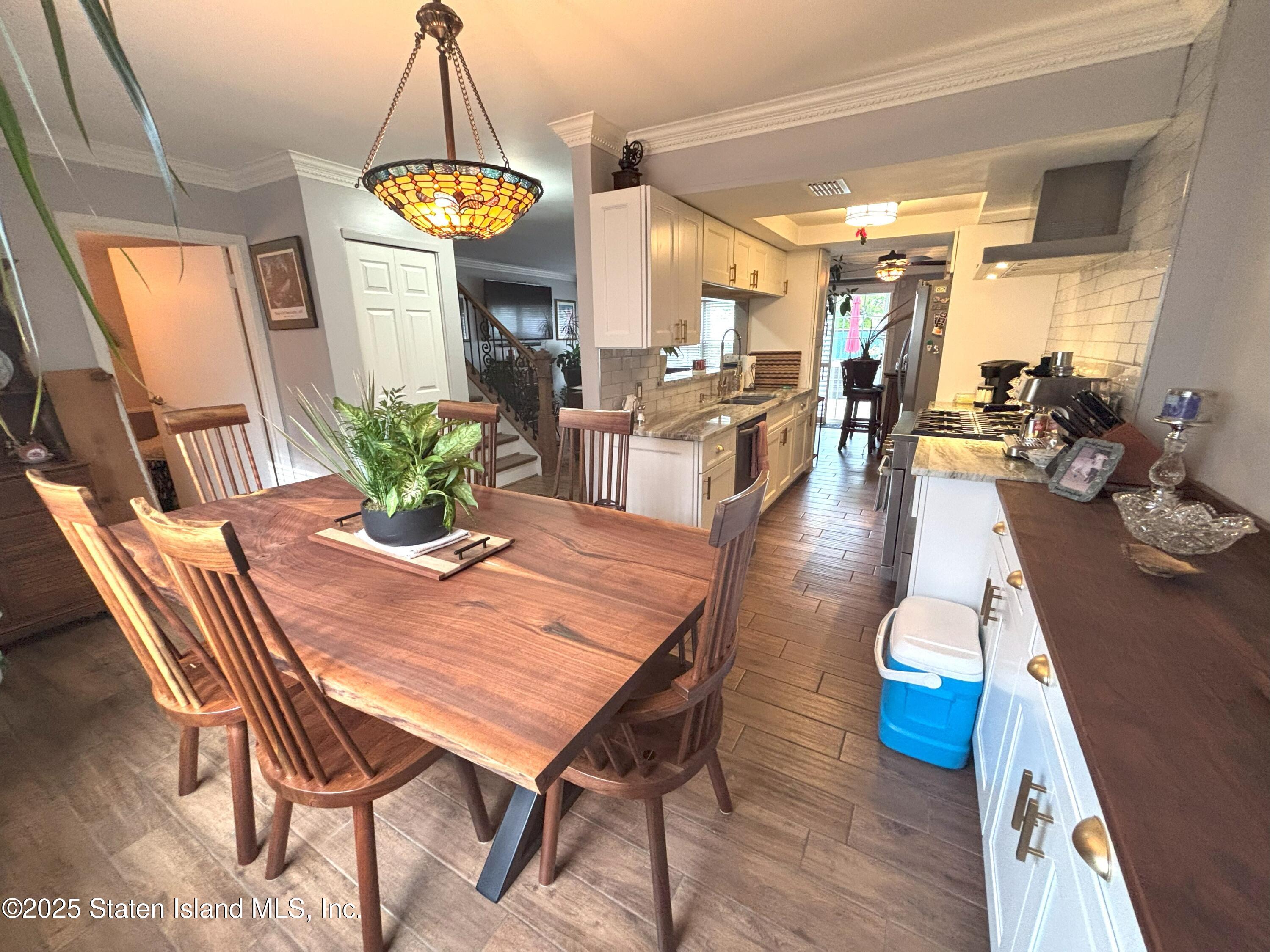 73 Hampton Green Staten Island, NY 10312 - Photo 4 of 28 a dining room with wooden floor a chandelier a wooden table and chairs