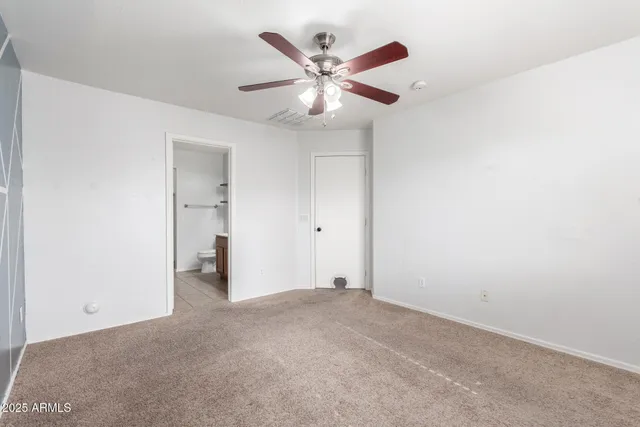 an empty room with closet and a ceiling fan