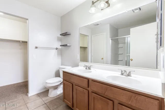 a bathroom with a double vanity sink a toilet and a mirror