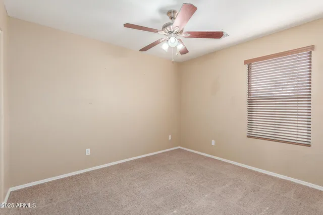 an empty room with a window and a fan