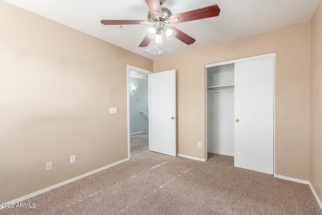 an empty room with closet and a ceiling fan