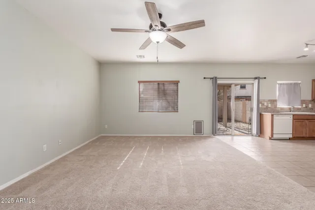 an empty room with chandelier fan and windows