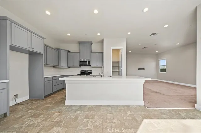 a large white kitchen with kitchen island a sink a stove a refrigerator and a cabinets