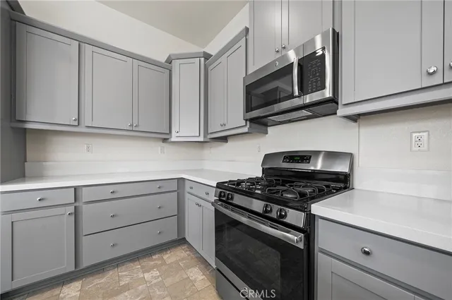 a kitchen with stainless steel appliances granite countertop grey cabinets a stove a sink and dishwasher