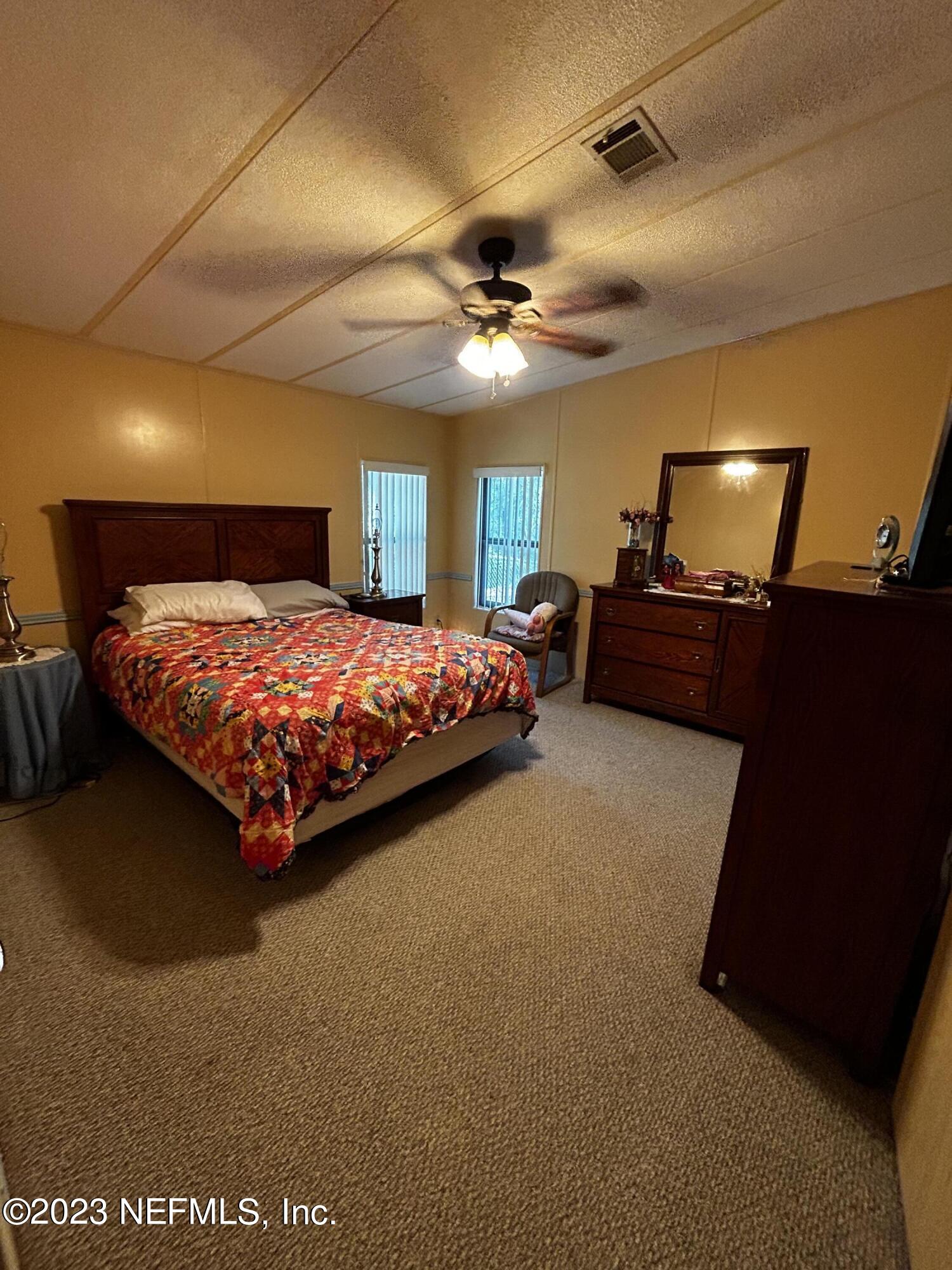 130 Walker Drive Interlachen, FL 32148 - Photo 22 of 31 a bedroom with a bed and a chandelier