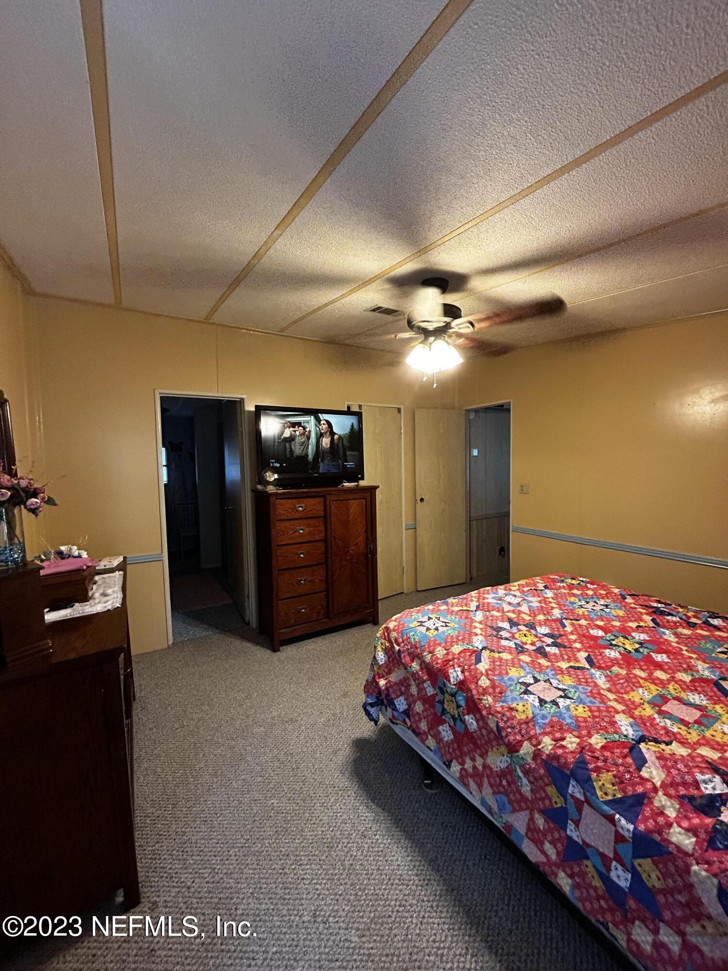 130 Walker Drive Interlachen, FL 32148 - Photo 23 of 31 a bedroom with a bed and a chandelier