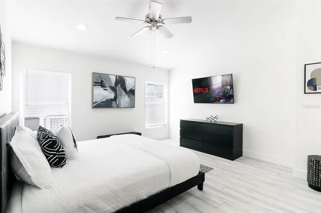 a bedroom with a bed a tv and wooden floor