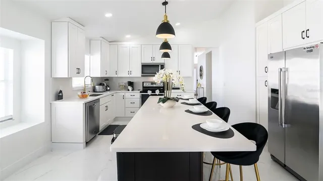 a kitchen that has a dining table chairs stainless steel appliances and cabinets