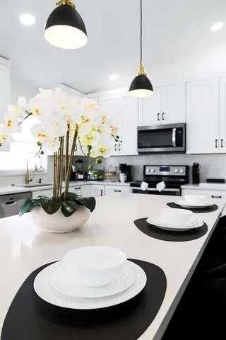 a kitchen with stainless steel appliances a stove a sink and a dining table
