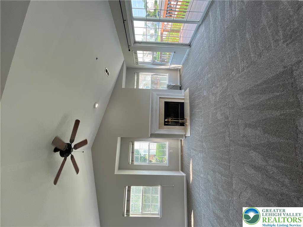A spacious room features vaulted ceilings, plush carpeting, and a cozy central fireplace.
