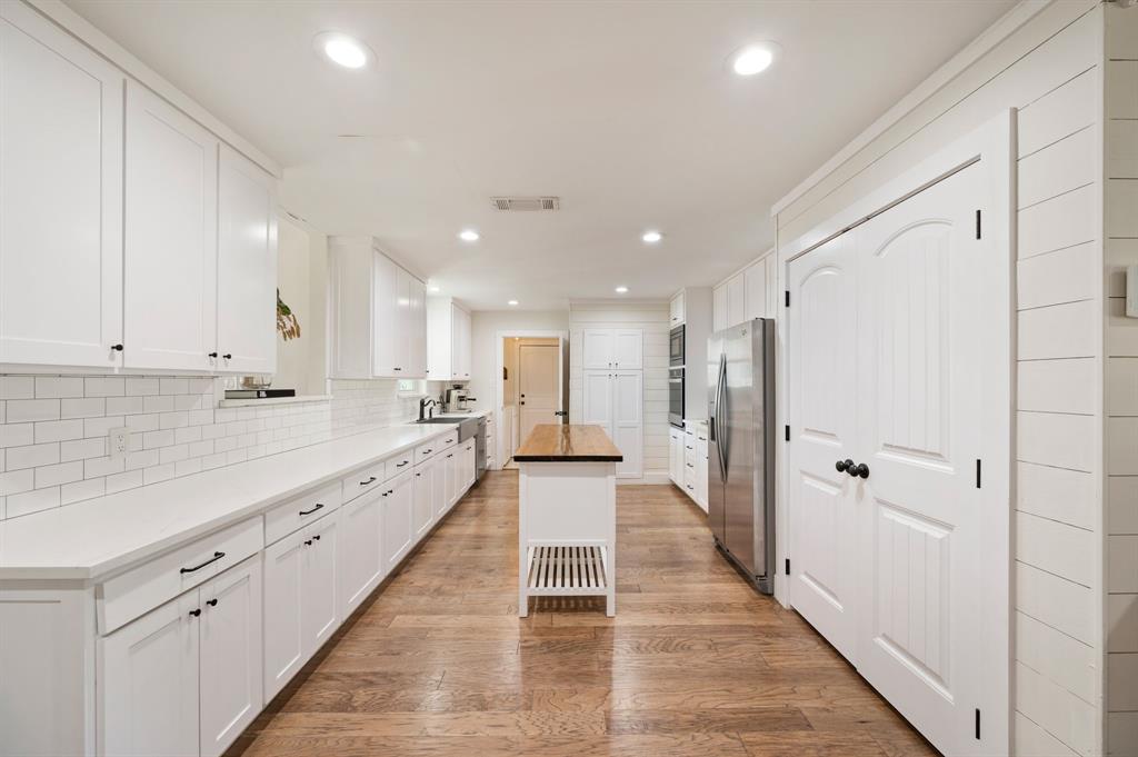 504 Main Street Roanoke, TX 76262 - Photo 8 of 40 a large white kitchen with a lot of counter space and wooden floor
