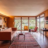 a living room with furniture large windows and wooden floor
