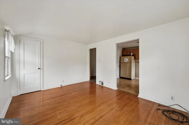 a view of an empty room with wooden floor and closet