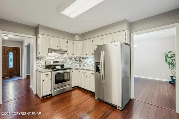 a kitchen with stainless steel appliances a refrigerator a stove top oven and wooden floor