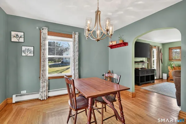 a kitchen with stainless steel appliances granite countertop a dining table chairs refrigerator and sink