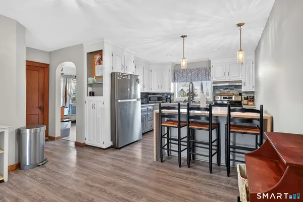 a room with stainless steel appliances kitchen island granite countertop a stove a sink a dining table and chairs