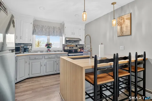 a kitchen with granite countertop a table chairs stove and white cabinets