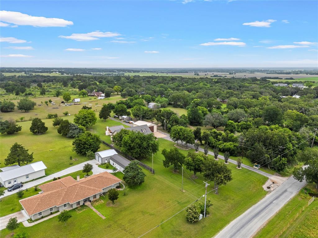 1117 Downsville Road Robinson, TX 76706 - Photo 37 of 40 Expansive property featuring a single-story residence with a terracotta-style roof, multiple outbuildings, mature trees, and a paved driveway, surrounded by green landscape