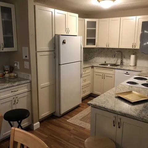 a kitchen with granite countertop a refrigerator stove and sink
