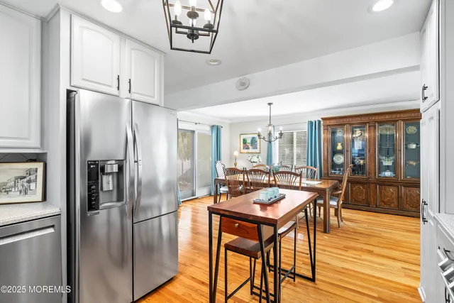 a kitchen with stainless steel appliances granite countertop a refrigerator a stove a dining table and chairs with wooden floor