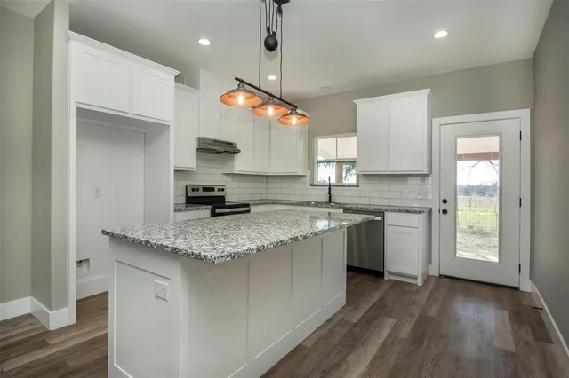 a kitchen with a sink a counter top space a large window and stainless steel appliances