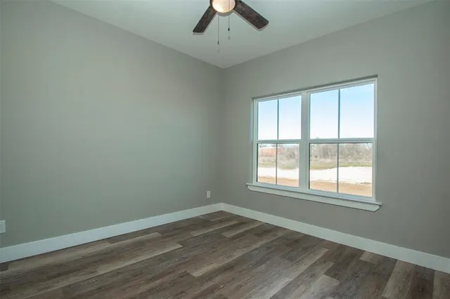 an empty room with a window and a chandelier fan