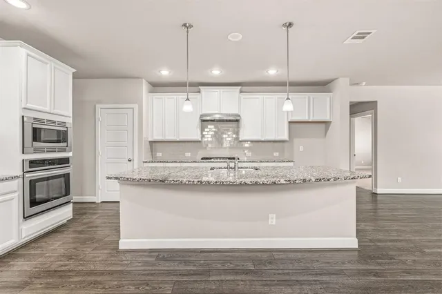 a large kitchen with granite countertop a stove a sink and a refrigerator