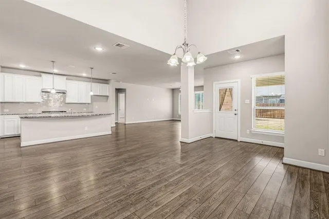 a view of an empty room and window wooden floor and a kitchen