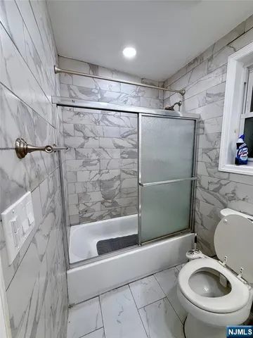 a bathroom with a granite countertop bathtub sink mirror and toilet