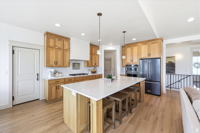 283 North 500 West Mapleton, UT 84664 - Photo 24 of 102 Kitchen featuring stainless steel appliances, a spacious island, double ovens, hanging light fixtures, and backsplash.