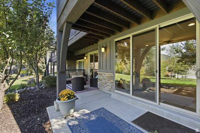 5207 North Oldgate Road Heber City, UT 84032 - Photo 39 of 58 Concrete patio with stacked stone accents, board and batten siding, and dual sliding glass doors