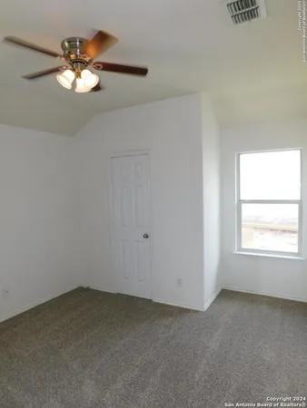 an empty room with a chandelier fan and windows