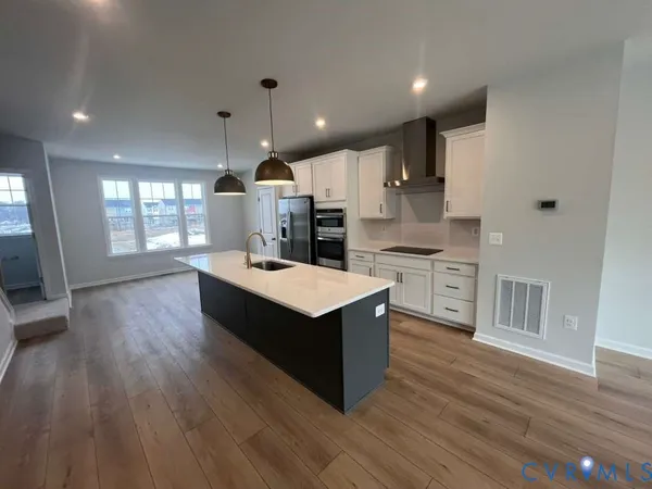a kitchen with stainless steel appliances kitchen island wooden floors wooden cabinets and entryway