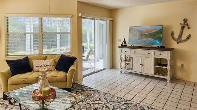 a living room with furniture a flat screen tv and a floor to ceiling window