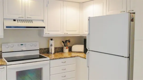 a kitchen with granite countertop cabinets and white appliances
