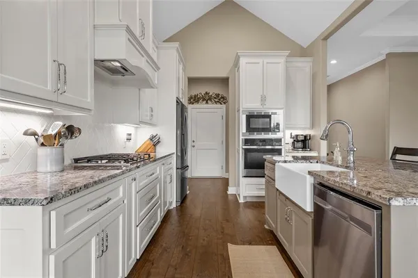a kitchen with stainless steel appliances granite countertop a stove top oven a sink and dishwasher