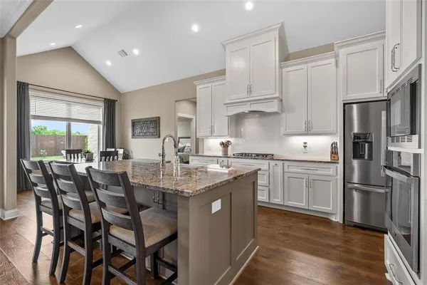 a kitchen with stainless steel appliances granite countertop a table chairs sink refrigerator and cabinets