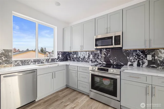 a kitchen with stainless steel appliances granite countertop a stove a sink and a microwave