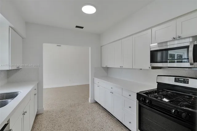a kitchen with granite countertop white cabinets and stainless steel appliances