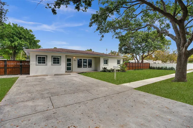 a view of house in front of a big yard with large trees