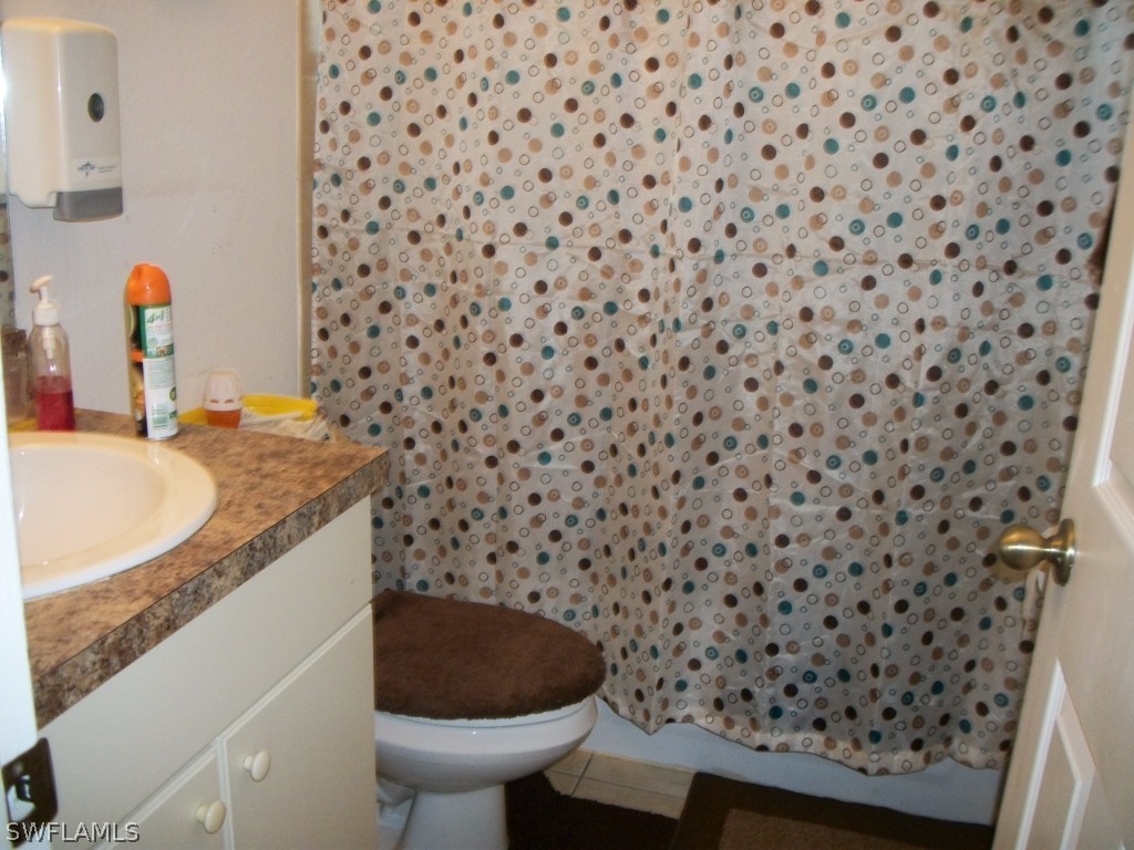 801 Meadow Road Lehigh Acres, FL 33973 - Photo 4 of 13 a bathroom with a sink a toilet and a mirror