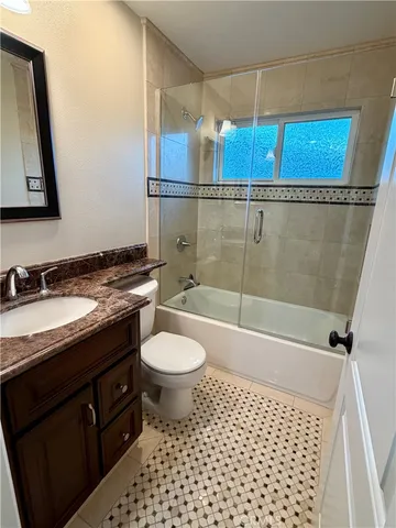 a bathroom with a granite countertop sink a toilet and shower