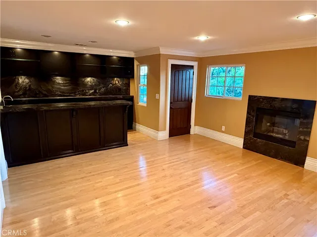 a view of an empty room with kitchen and window