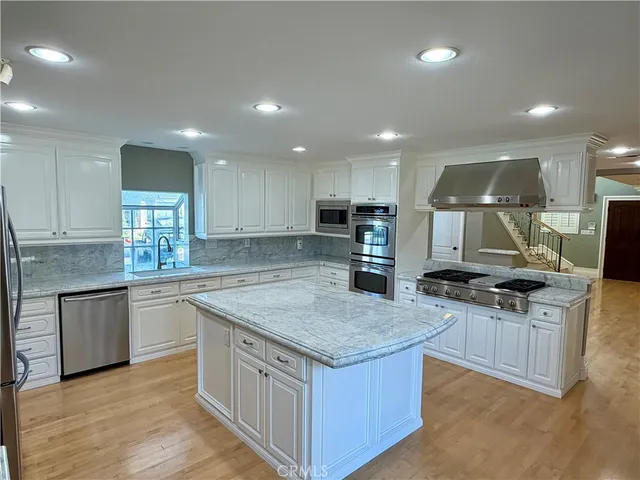 a kitchen with stainless steel appliances granite countertop a kitchen island a stove and a sink