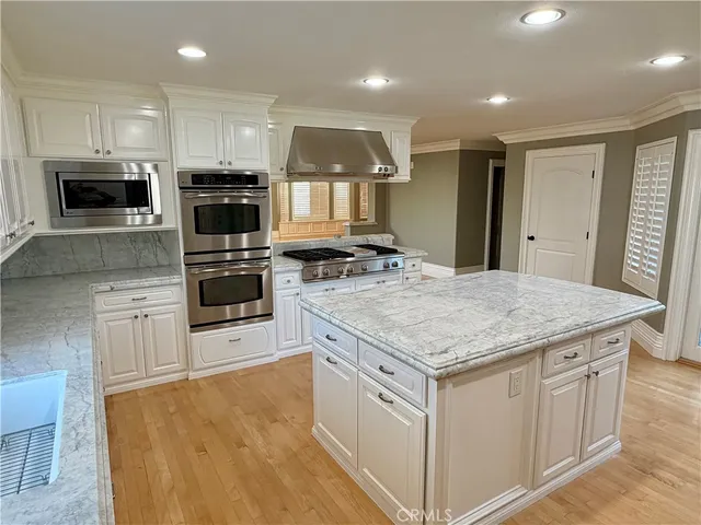 a kitchen with stainless steel appliances granite countertop a stove top oven a sink and a microwave