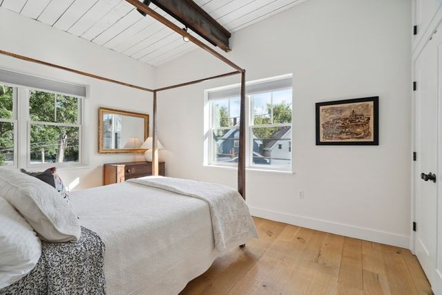 a bedroom with a bed painting on the wall and a window