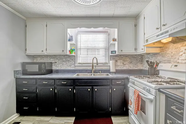 a kitchen with granite countertop a sink a stove and cabinets