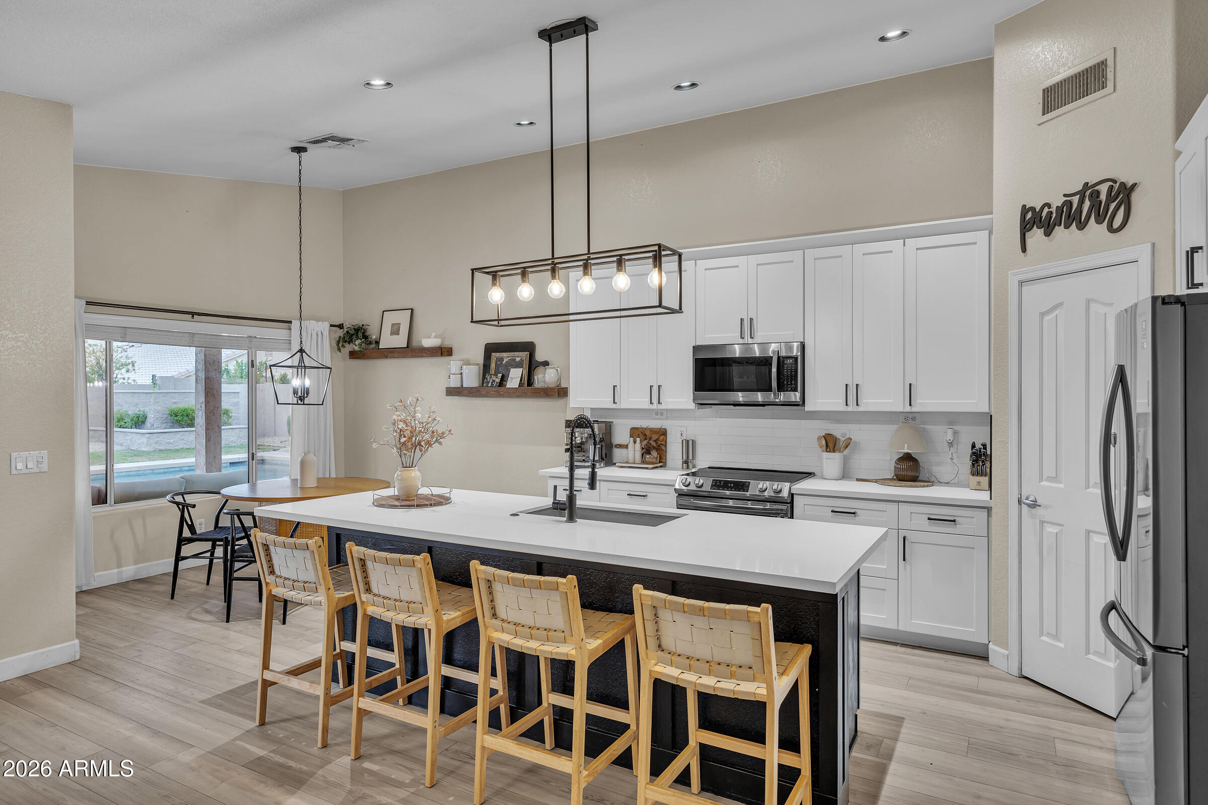 4629 East Gold Poppy Way Phoenix, AZ 85044 - Photo 8 of 46 a kitchen with stainless steel appliances kitchen island granite countertop a dining table chairs and white cabinets