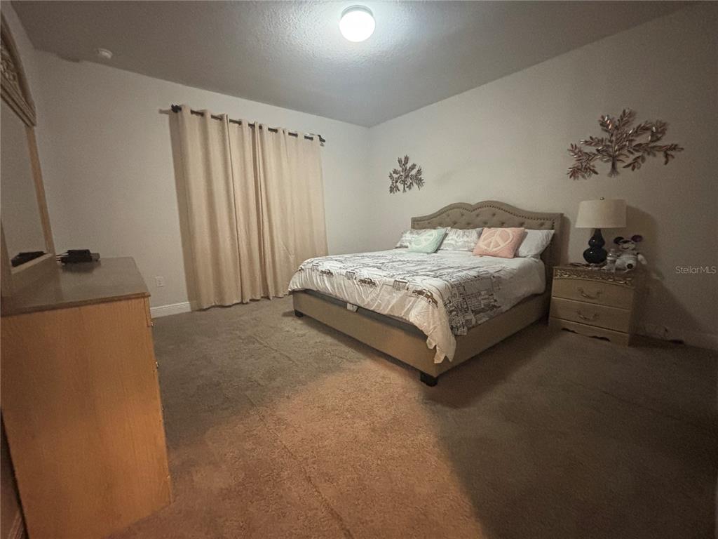 1222 Yorkshire Court Davenport, FL 33896 - Photo 15 of 17 a spacious bedroom with a bed and a painting on the wall