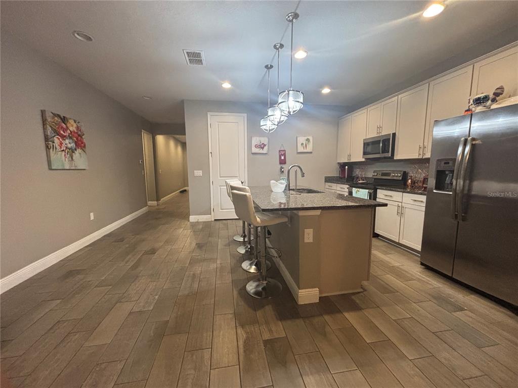1222 Yorkshire Court Davenport, FL 33896 - Photo 9 of 17 a kitchen with stainless steel appliances granite countertop a sink a stove a refrigerator cabinets and wooden floor